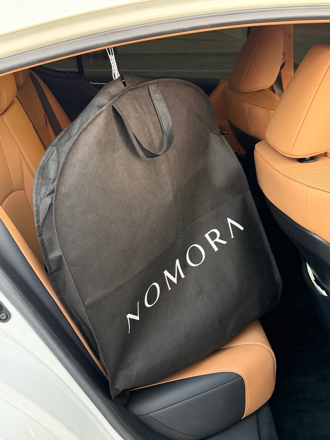 Black NOMORA garment bag on the rear seat of the car
